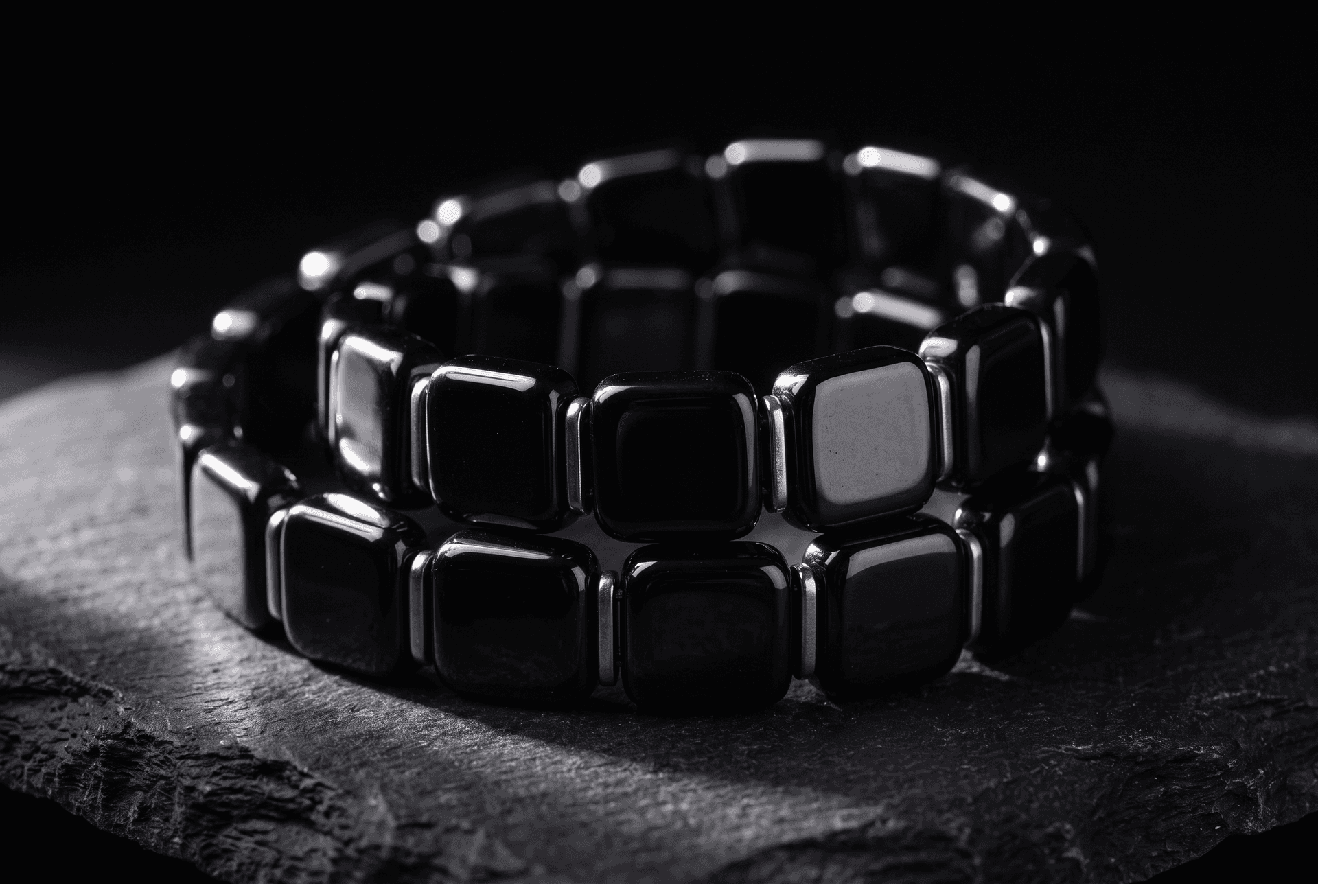 Macro photograph of a black tourmaline beaded bracelet with square-cut stones on a dark surface