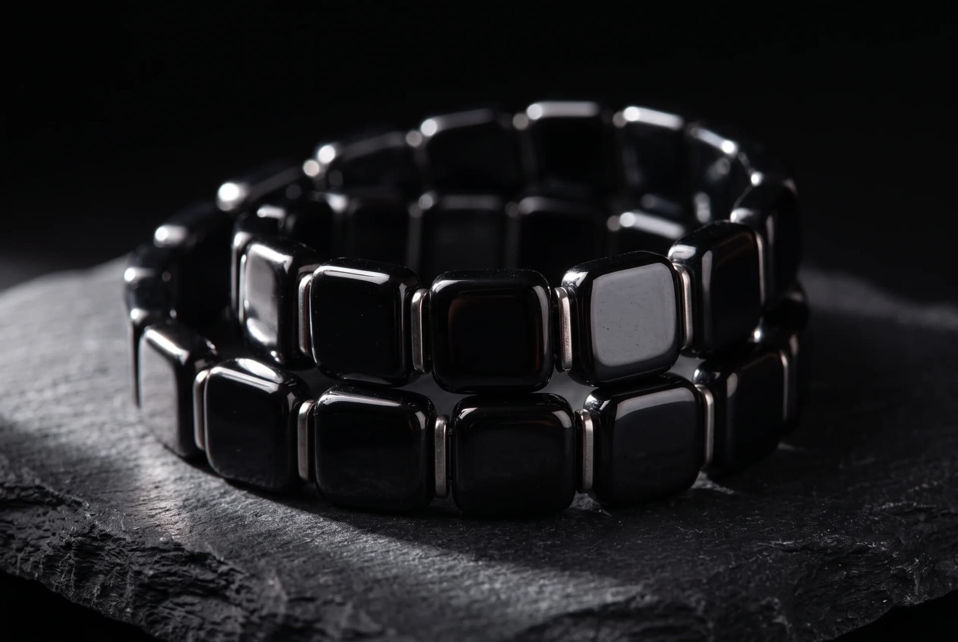 Macro photograph of a polished hematite beaded bracelet on a dark surface