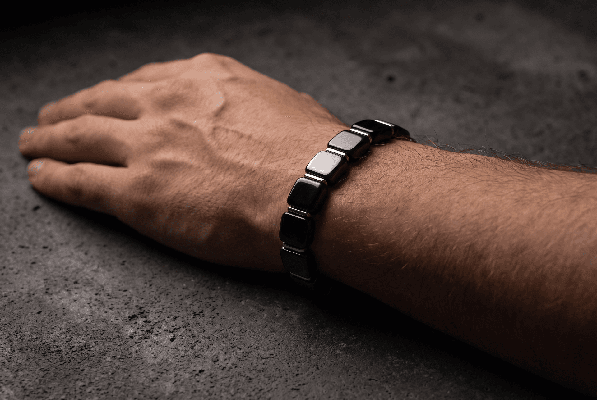 Close-up photograph of a man's hand and wrist wearing a black stone beaded bracelet