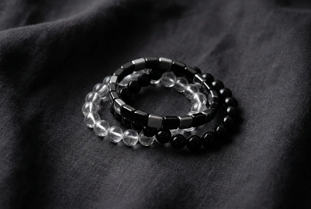 Assortment of natural stone beaded bracelets including an iridescent rainbow-finished piece, arranged on a dark linen surface
