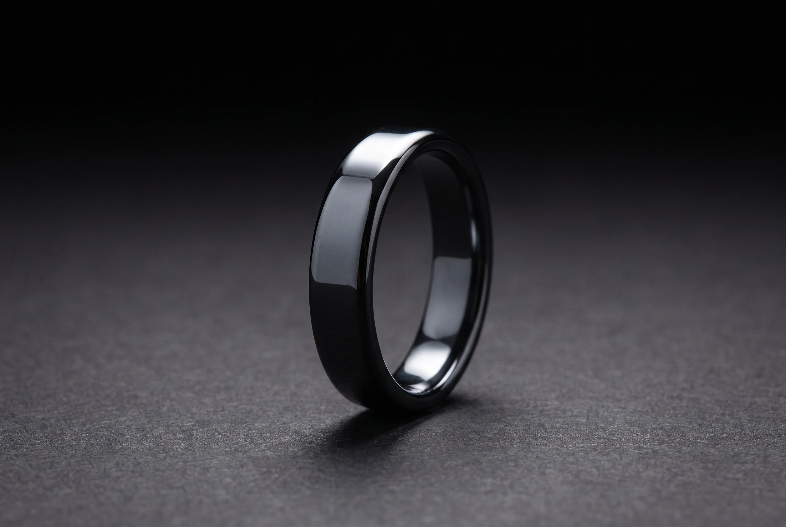 Macro studio photograph of the Hematite Band Ring standing upright against a dark background with a single specular highlight