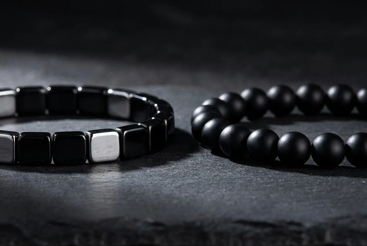 Side-by-side comparison of a metallic-black hematite bracelet and a lighter quartz-family bracelet on a dark surface